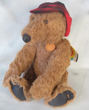 Large tan teddy bear with red buffalo plaid deerstalker cap