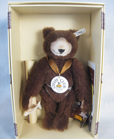 Dark brown teddy bear with a tan face and ceramic medallion