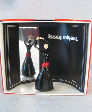 Pixi figurine of model wearing red and black Issey Miyake design